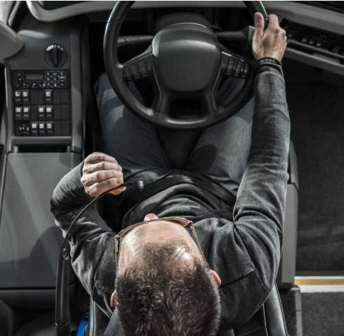 a driver sitting at the wheel of a charter bus