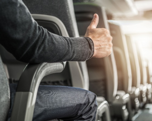 a charter bus passenger sits and gives a thumbs up